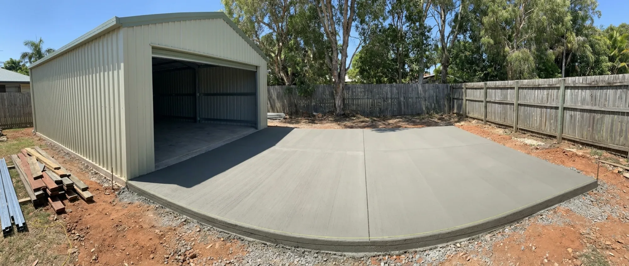 Newly poured broom-finish concrete shed slab and apron under a Colorbond steel shed