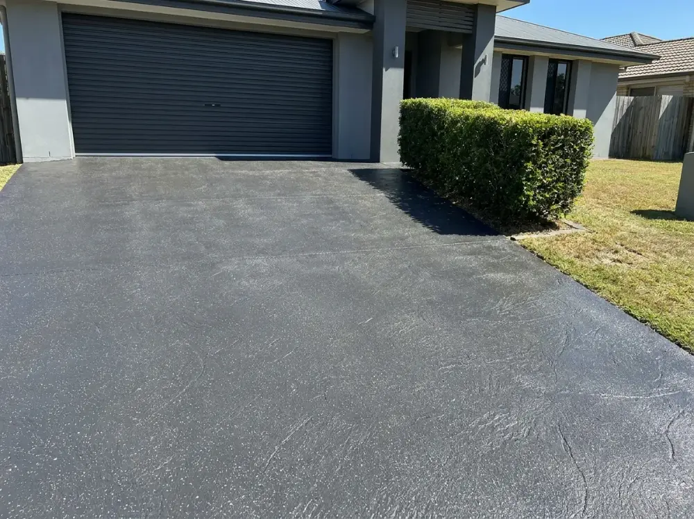 Charcoal seamless slate driveway with a low satin sealer sheen at a rendered Brisbane home