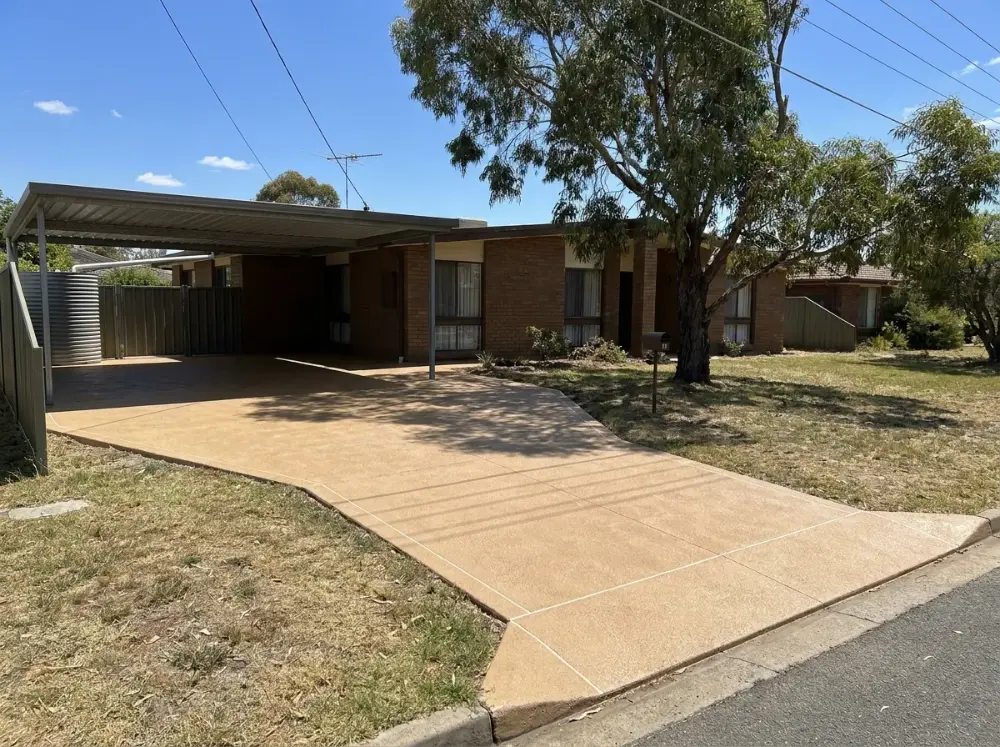 Sandstone-tan decorative concrete driveway in a running ashlar block pattern on a corner block