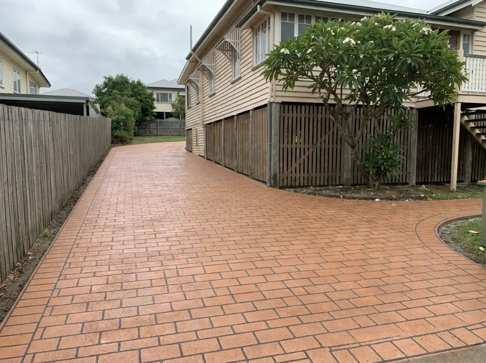 Red-brown brick-bond pattern concrete driveway with charcoal grout lines at a Queenslander