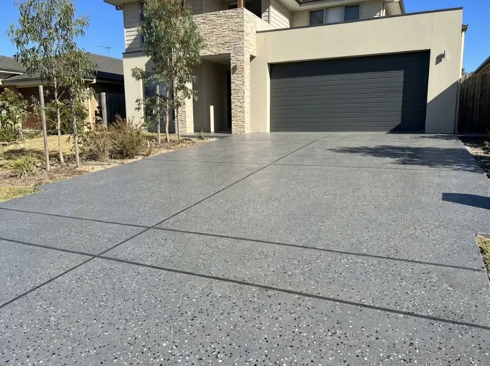 Mid-grey speckled decorative concrete driveway with black and white flecks and dark saw-cut joints