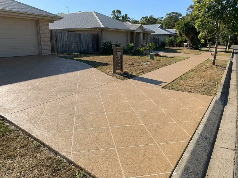 Tan square-tile decorative concrete driveway, kerb crossover and matching front footpath