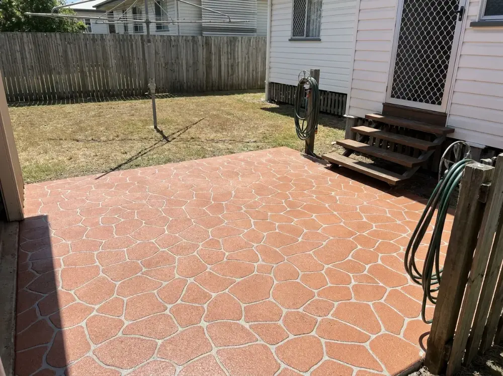 Small back patio resurfaced in a terracotta bush rock crazy-paving pattern with grey grout