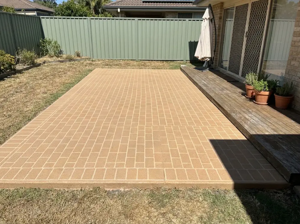 Tan brick-bond decorative concrete alfresco slab meeting an existing timber deck