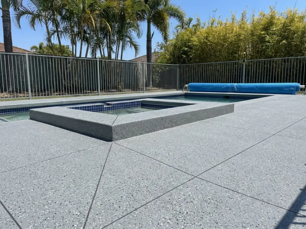 Mid-grey speckled non-slip concrete pool and spa surround with charcoal grout lines