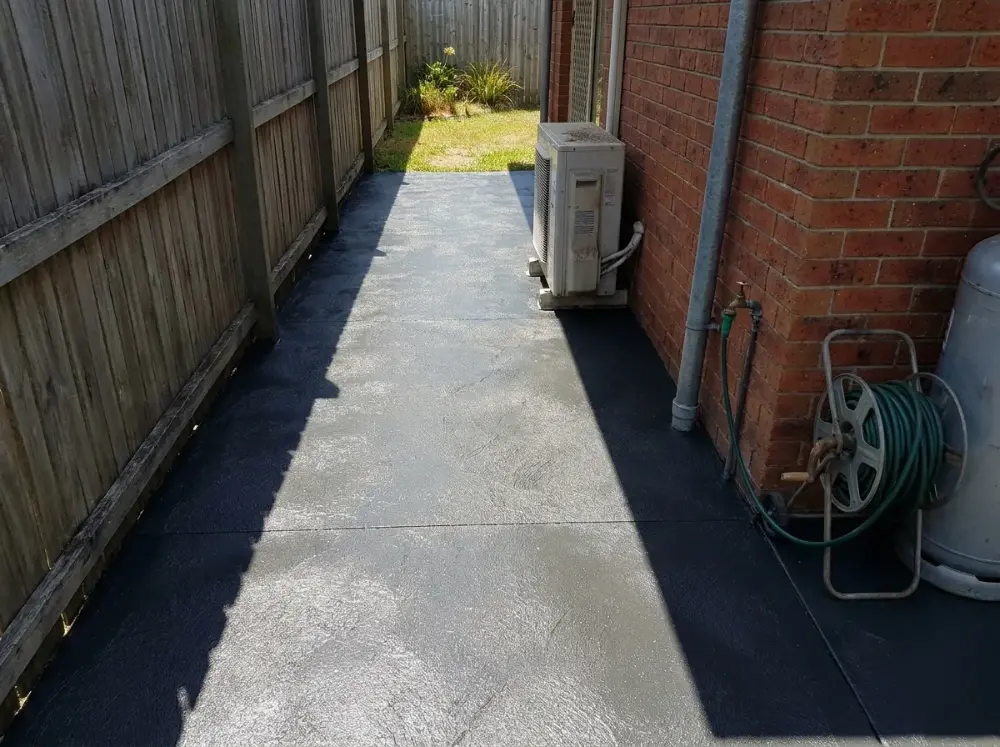 Narrow charcoal seamless slate side path running between a brick wall and a timber fence