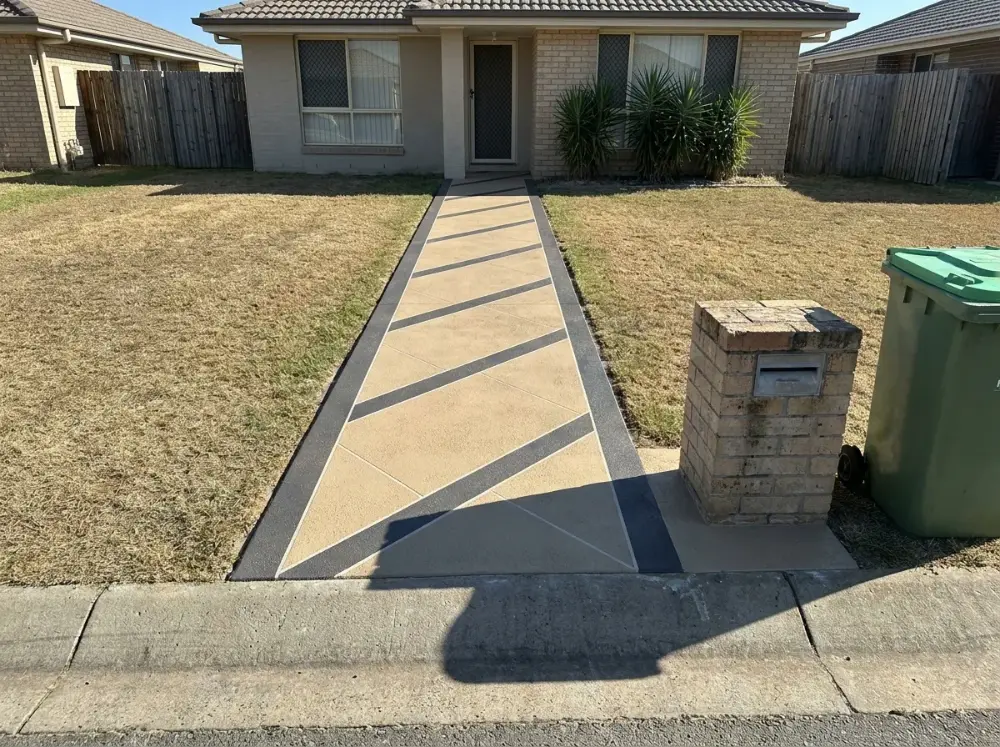 Sand-toned concrete footpath with crossed charcoal diagonal banding cut through the overlay