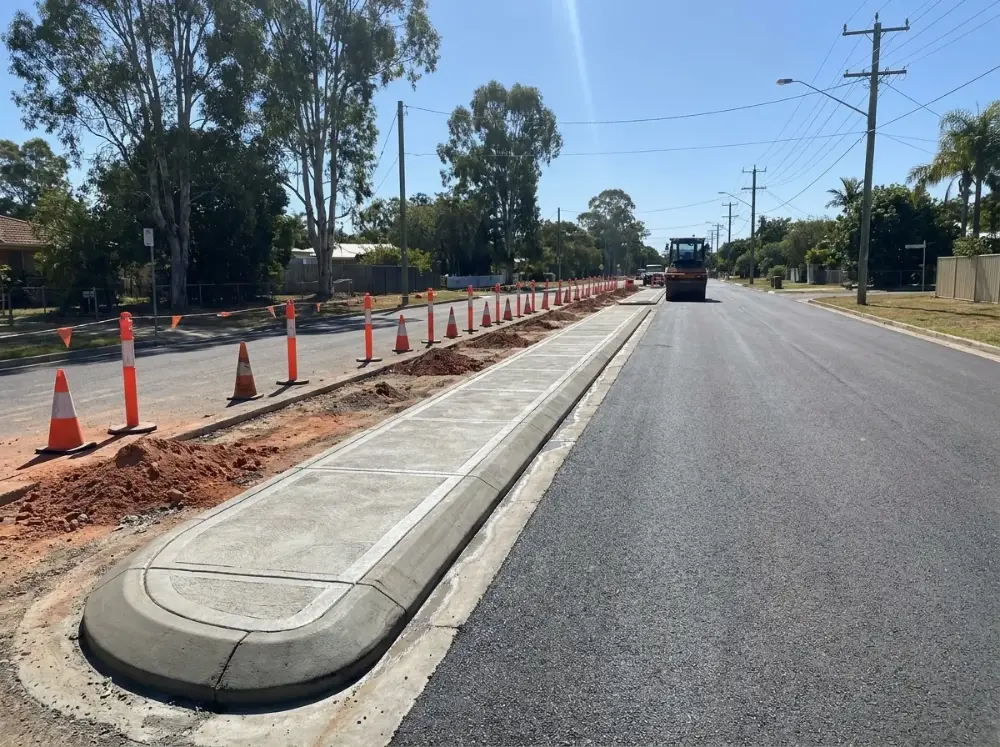 Machine-laid grey concrete kerbing and traffic island against new asphalt in a suburban street